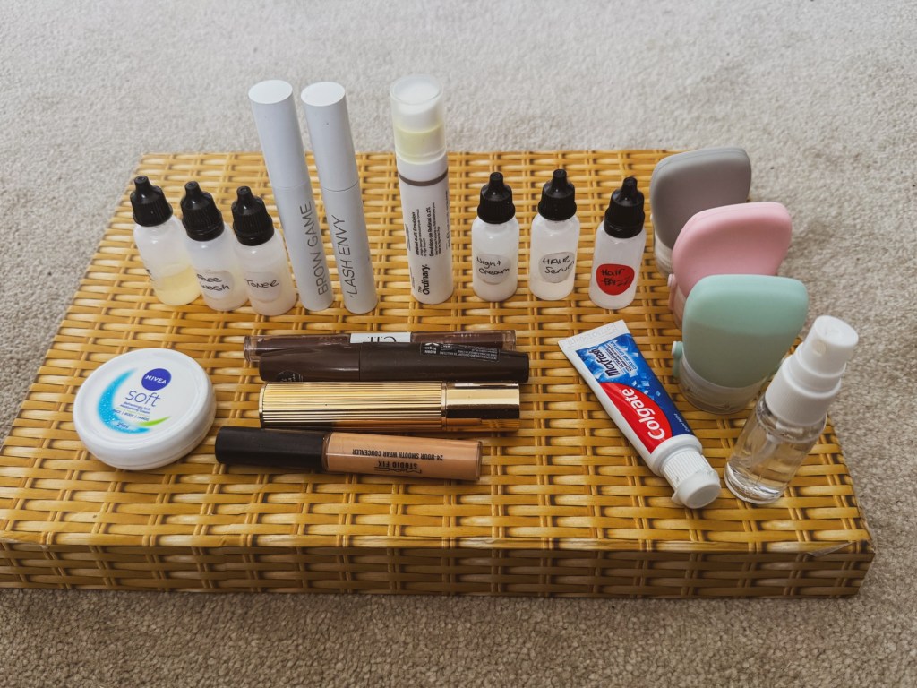 Complete travel skincare routine decanted into miniature labelled bottles and small toiletry containers.